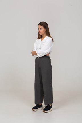 Three-quarter view of an upset young lady in office clothing embracing herself