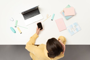 Une employée de bureau à la table tenant le téléphone