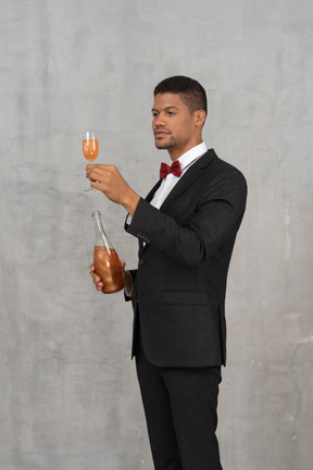 Man in suit and bow tie looking at a glass of champagne