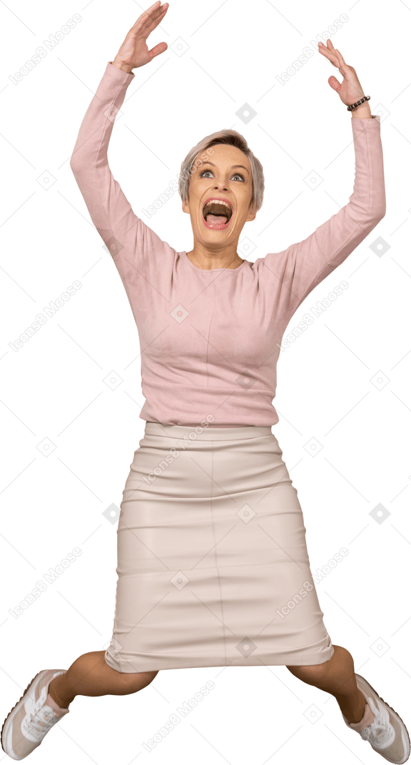腕を上げてジャンプするカジュアルな服を着た幸せな女性の正面図