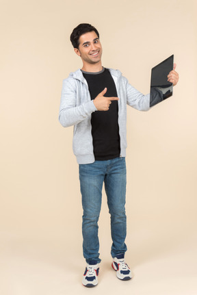 Young caucasian man pointing at a digital tablet he's holding