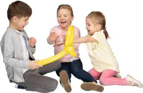Дети веселятся, играя с желтым воздушным шаром