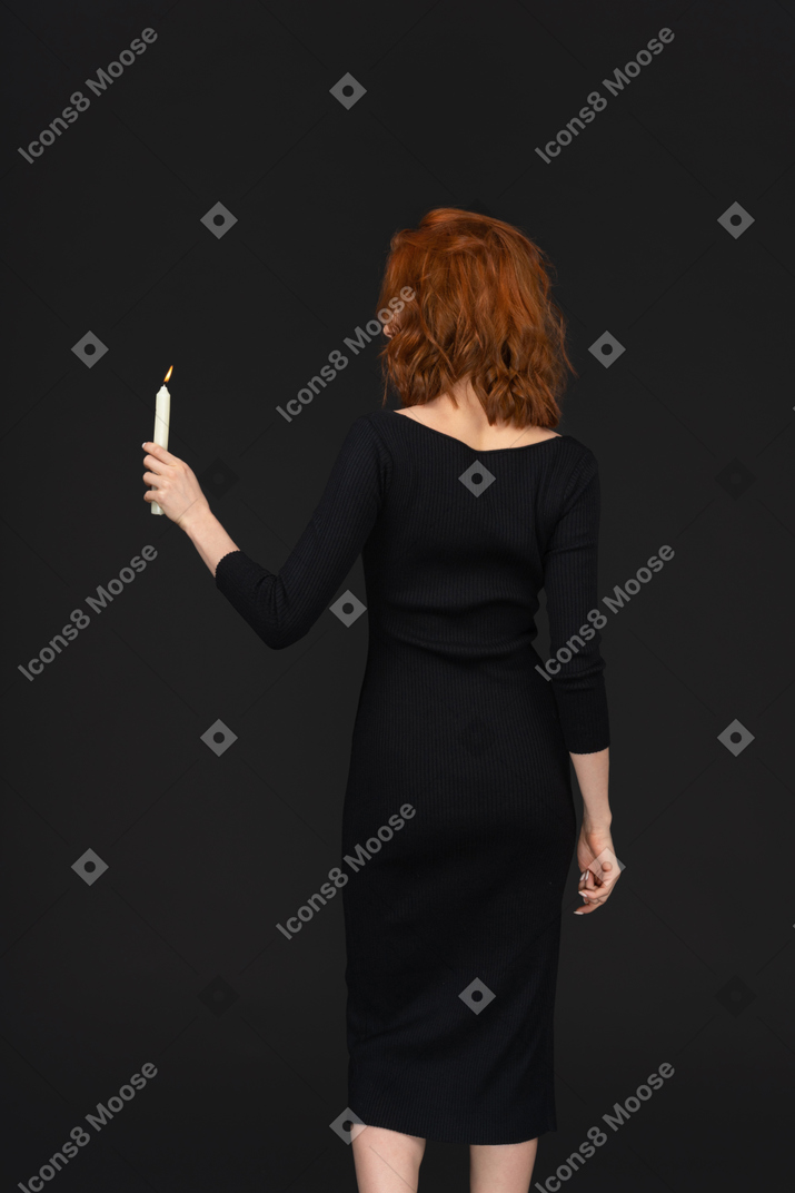A back side view of a cute girl holding a candle