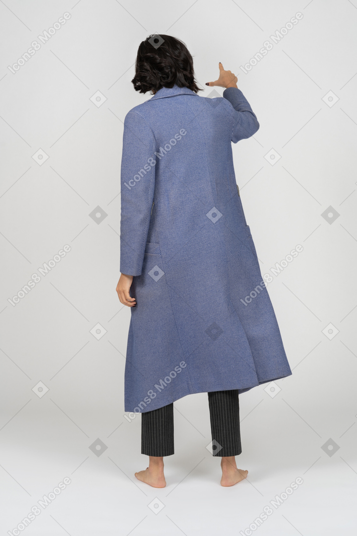Vue arrière d'une femme en manteau pointant son doigt