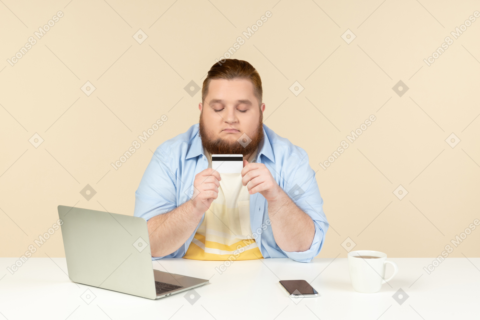Jovem homem com excesso de peso, sentado à mesa e olhando para o cartão do banco