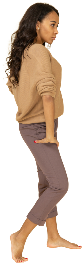 Vista lateral de una mujer joven de piel oscura poniendo la mano en la cadera