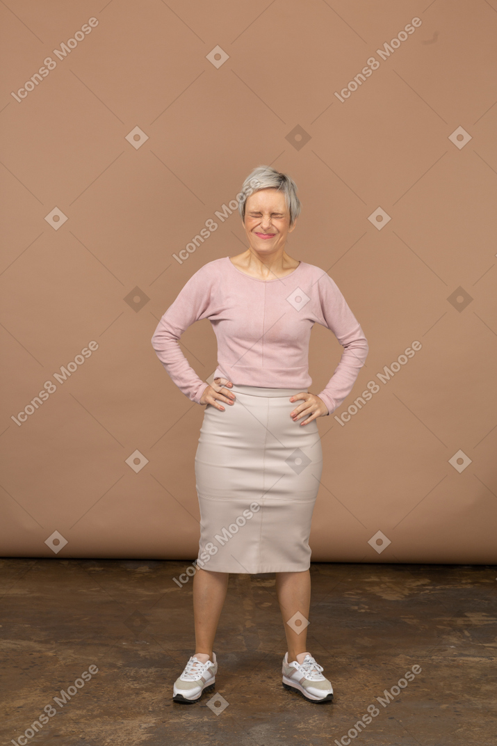 Front view of an emotional  woman in casual clothes standing with hands on hips