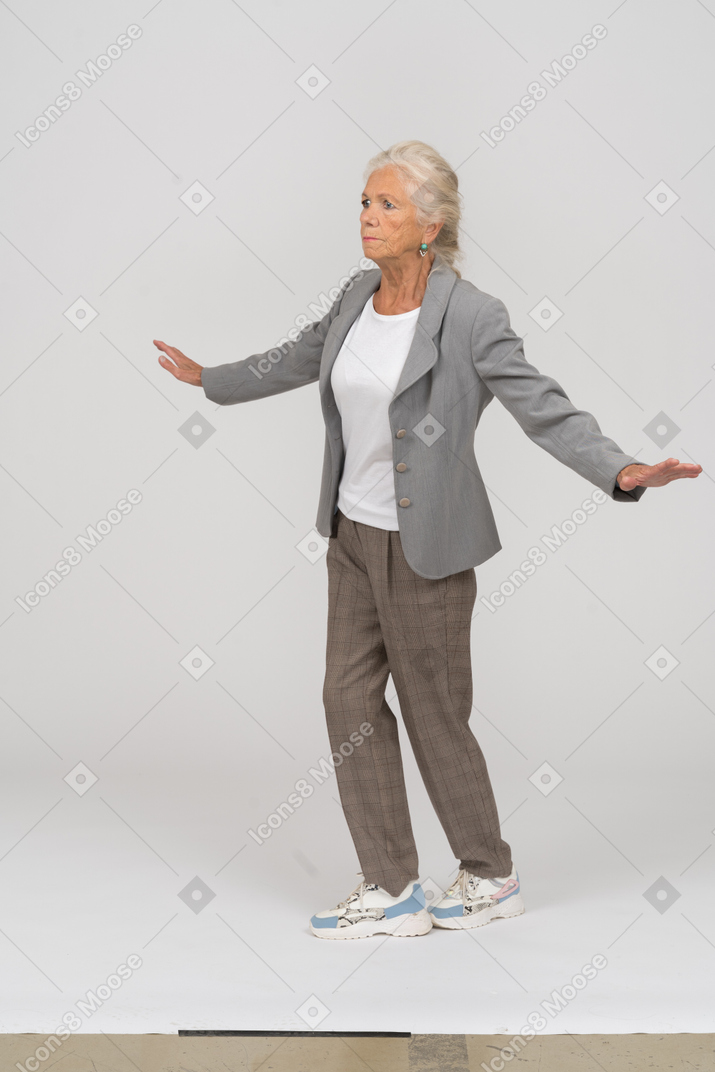 一位身着西装的老妇人张开双臂站立的前视图