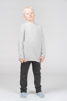 Front view of a confident kid blonde boy in casual clothes