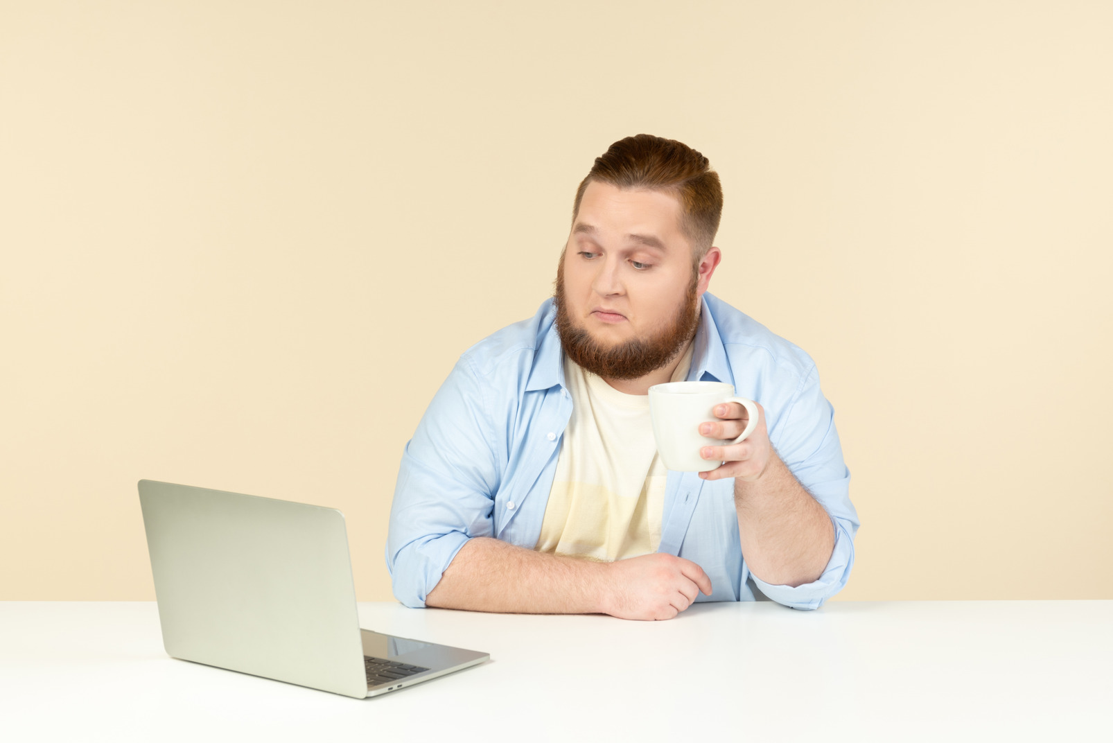 Interested in something young overweight sitting in front of laptop and having tea