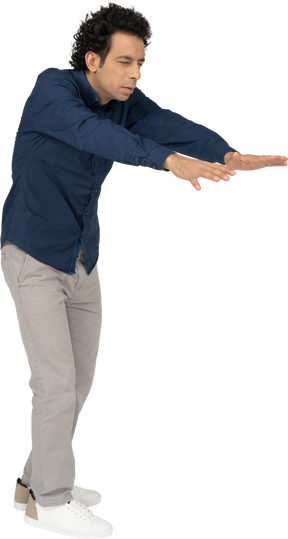 Vista lateral de um homem com roupas casuais se curvando com os braços estendidos