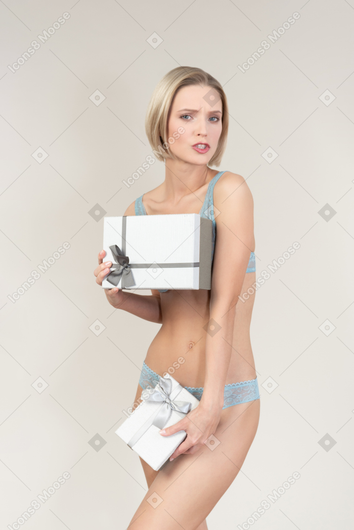 Sexy young woman in lingerie covering herself with gift boxes