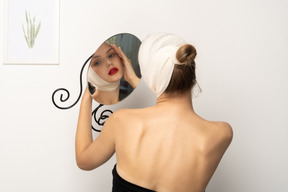 Young woman with head bandage holding a mirror