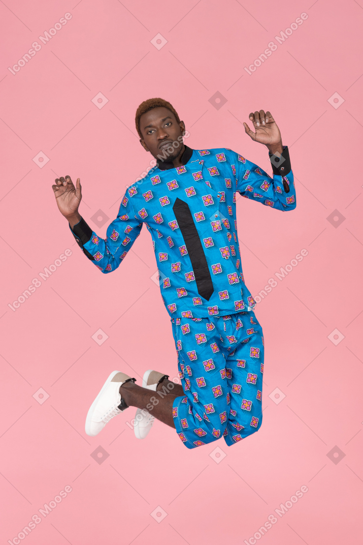 Hombre negro en pijama azul saltando sobre fondo rosa
