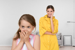 A woman in a yellow raincoat and a little girl standing in a living room