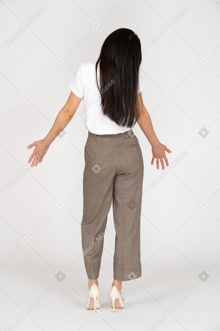 一位年轻的女士，穿着马裤和t恤，伸出她的手的后视图