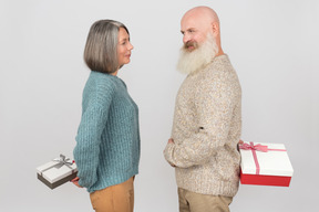 Elegant elderly couple giving gifts to each other