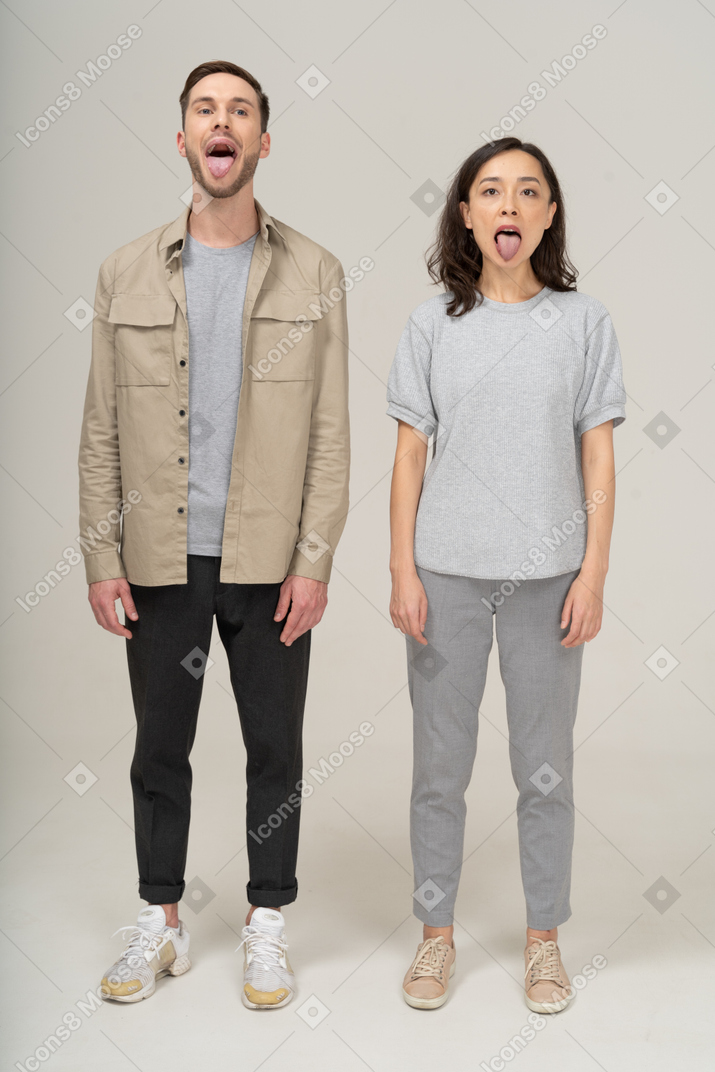 Vista frontal do jovem casal mostrando suas línguas