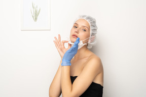 Young woman in surgical cap removing mask