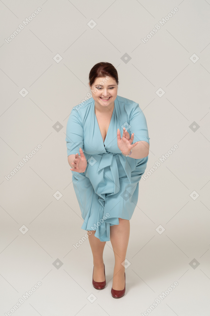 一个穿着蓝色裙子的快乐女人的前视图，显示某物的大小