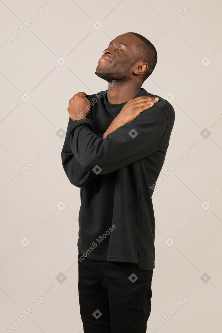 Man with eyes closed embracing himself