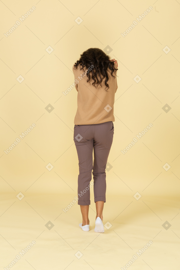 Vista posterior de una joven de piel oscura retraída abrazándose a sí misma