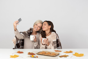 Mulheres jovens tomando café e tomando selfie