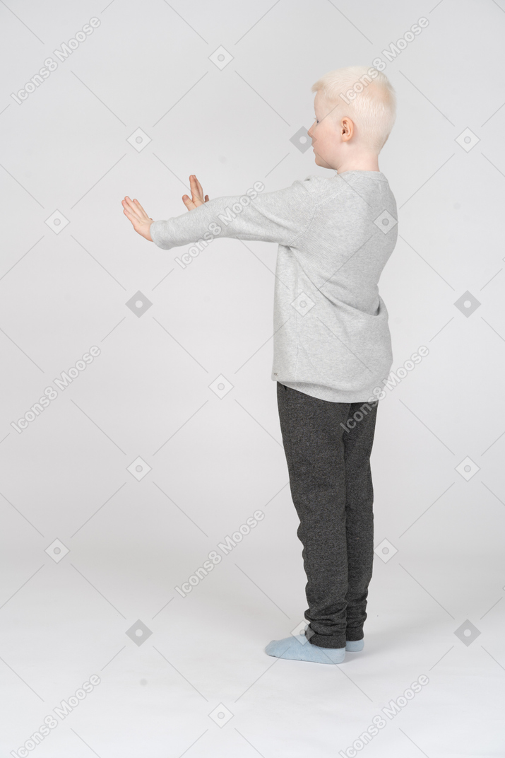 Petit garçon debout avec les bras tendus
