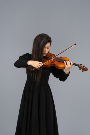 Close-up de uma jovem infeliz de vestido preto tocando violino