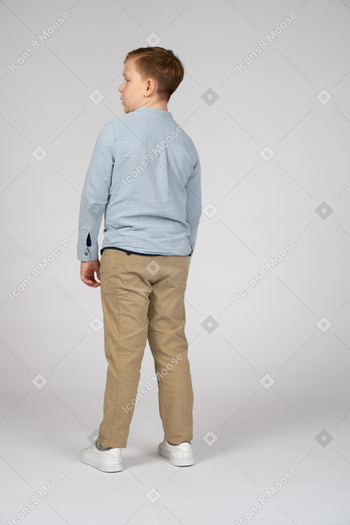 Vista traseira de um menino em roupas casuais, olhando de lado