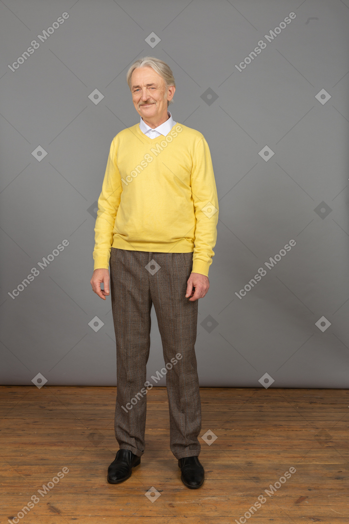 黄色套头衫的老开朗男人微笑着，看着相机的前视图