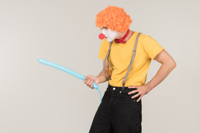 Mad looking male clown holding balloon