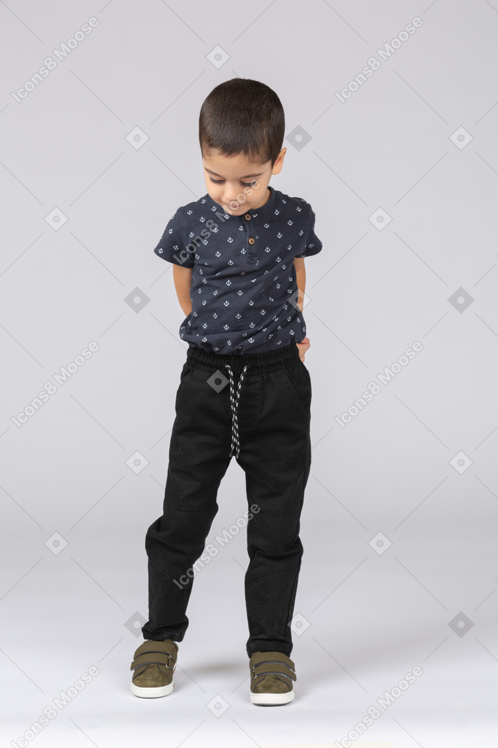 Vista frontal de un niño tímido en ropa casual mirando hacia abajo