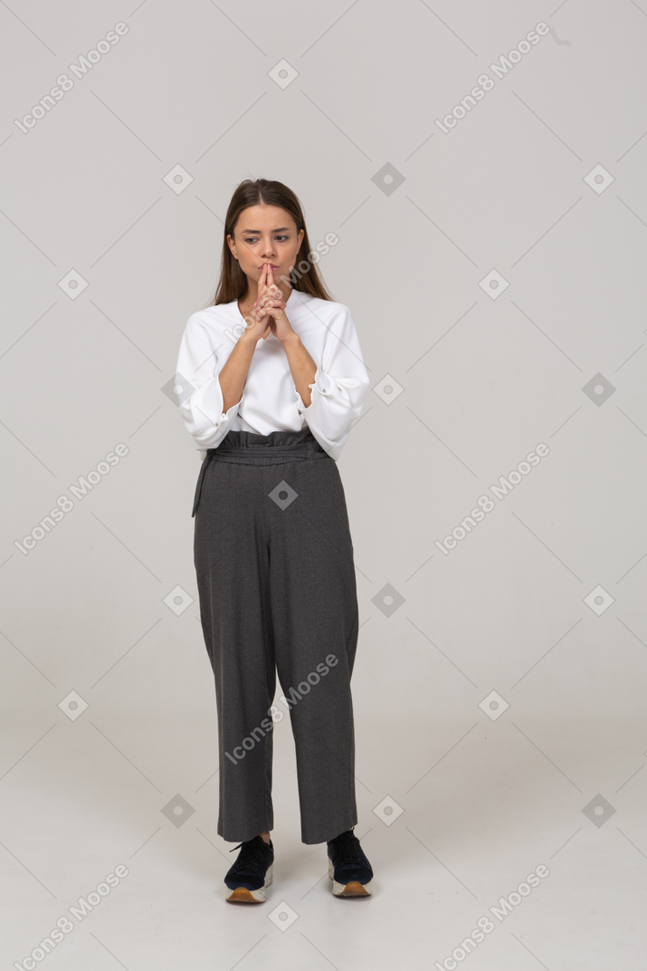 Front view of a thoughtful young lady in office clothing holding hands together