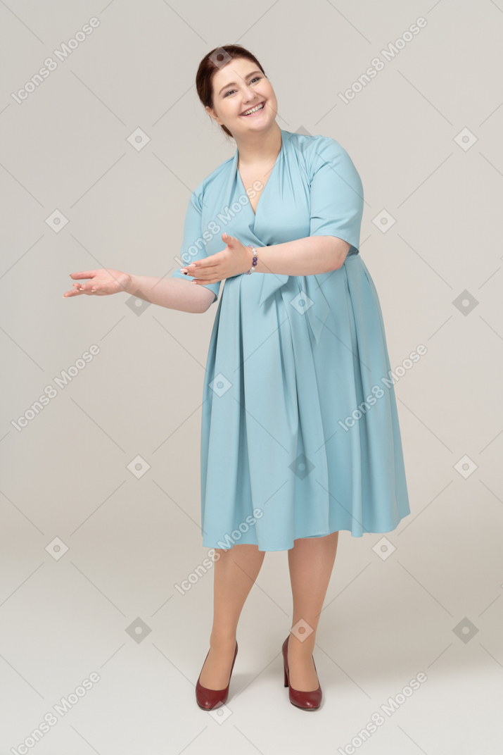 Vista frontal de uma mulher de vestido azul cumprimentando alguém