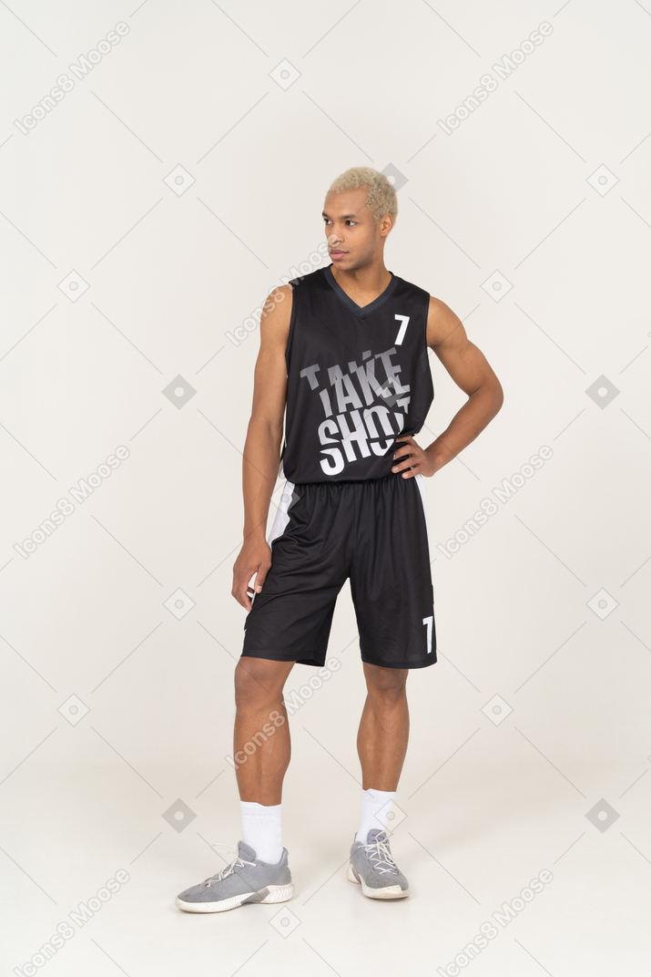 一名年轻男篮球运动员把手放在臀部，看向一边的前视图