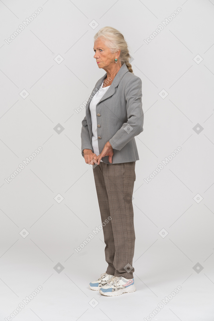 Вид сбоку пожилой женщины в костюме, касающейся ее руки