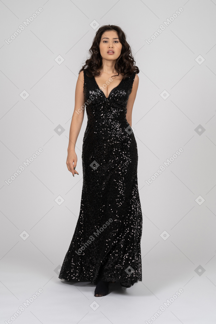 Красивая женщина в черном вечернем платье позирует модно