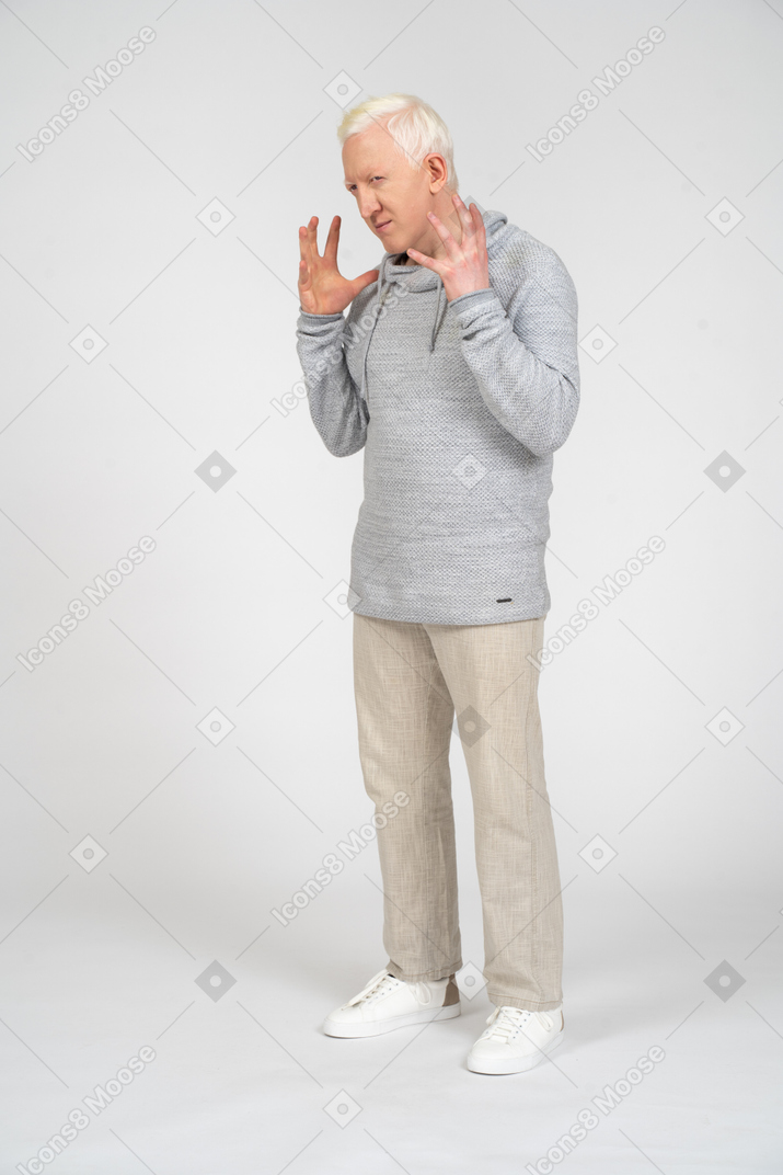 Vista de três quartos de um homem de pé com os dedos abertos perto do rosto