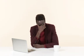 Elegante hombre negro sentado a la mesa en la oficina