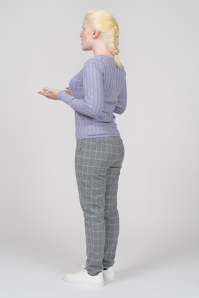 Вид сзади в три четверти на молодую женщину в повседневной одежде, говорящую