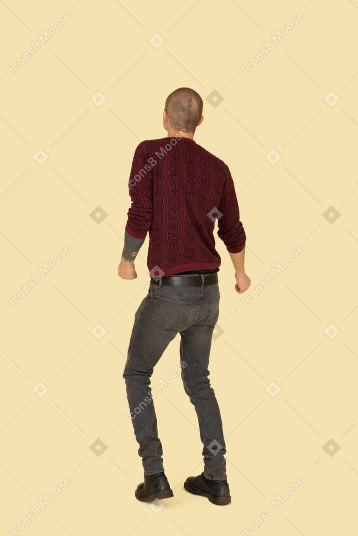 赤いプルオーバーに身を包んだ踊っている若い男の背面図