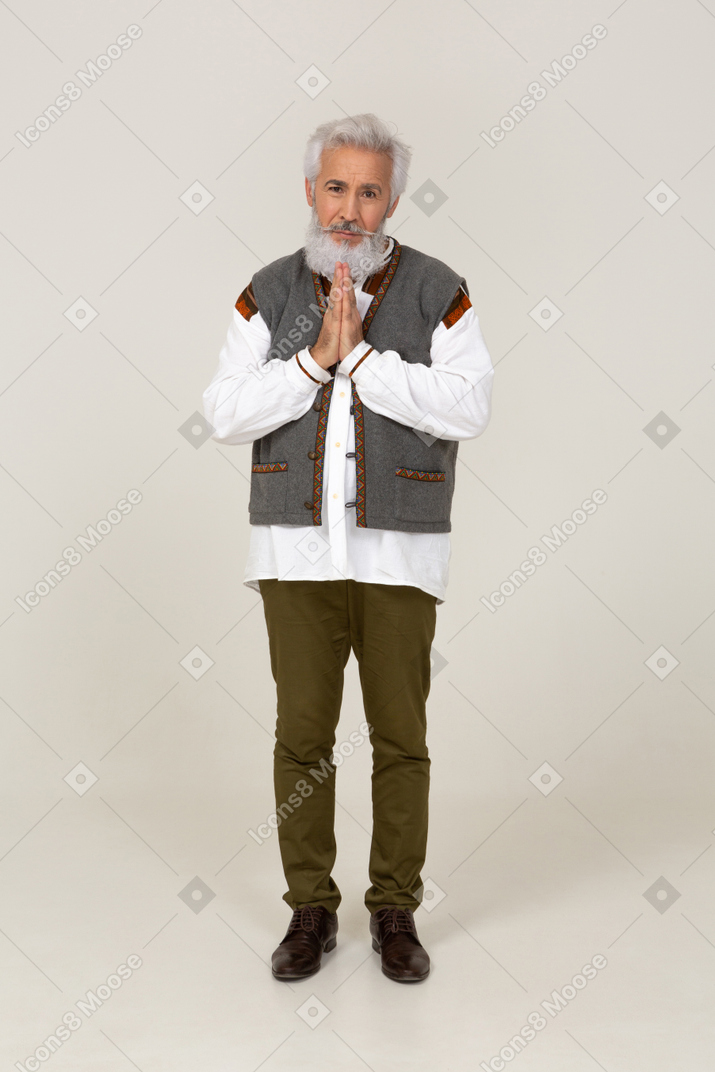 Man in gray vest standing with folded hands