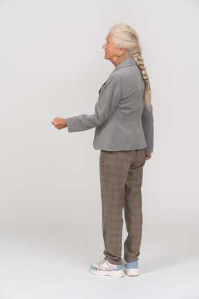 Side view of an old woman in suit showing fist