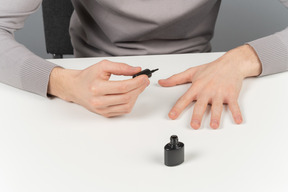 Un homme utilise un vernis à ongles noir