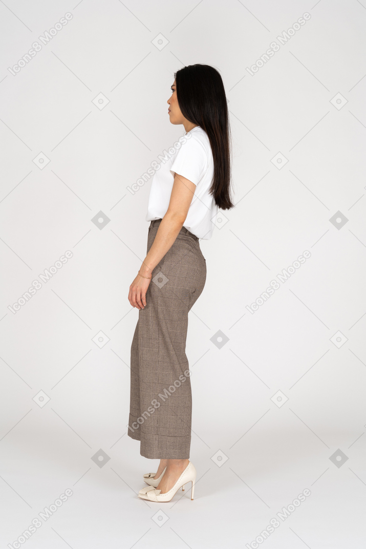 Vista laterale di una giovane donna perplessa in calzoni e maglietta