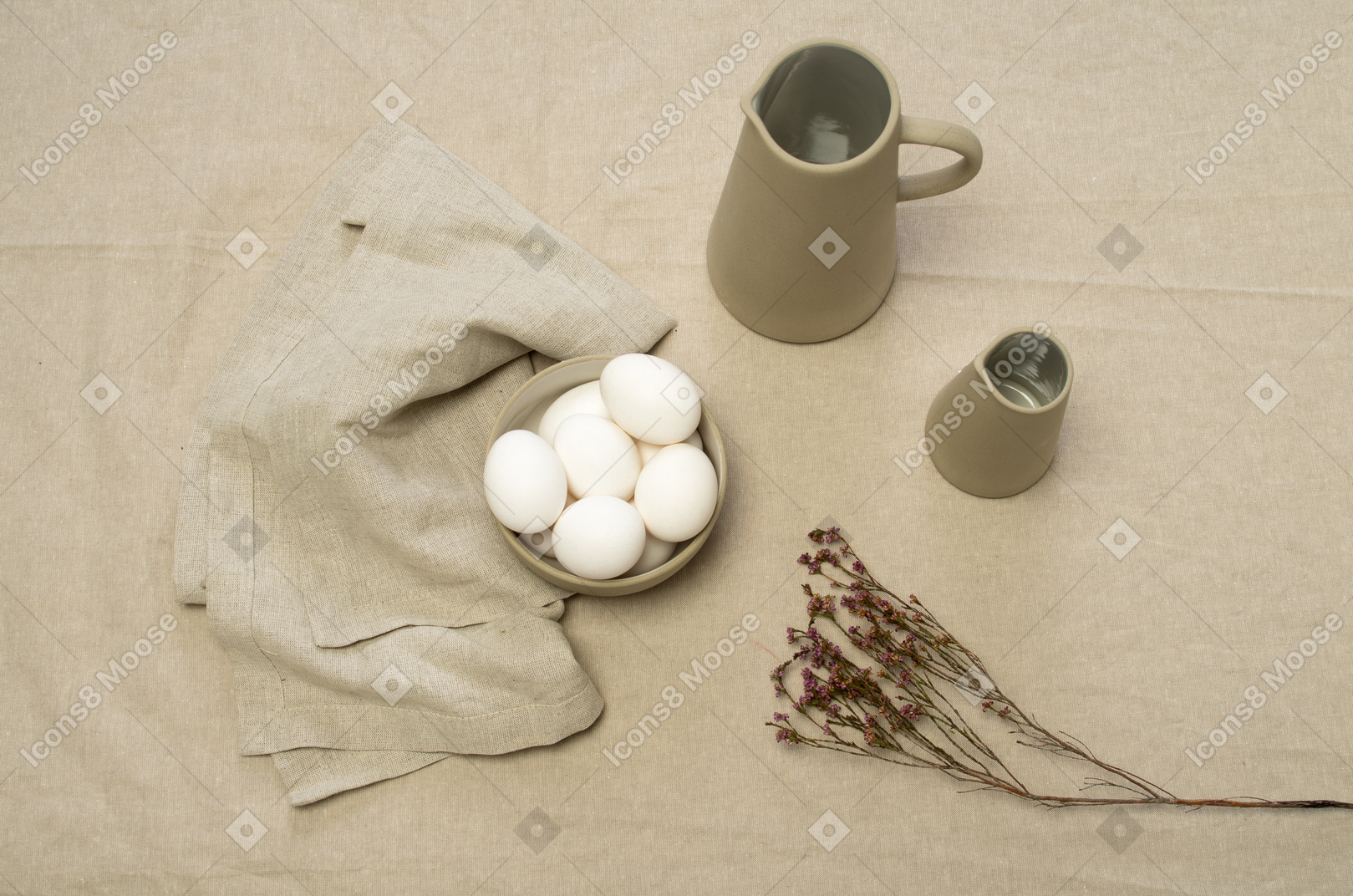 A bowl of chicken eggs and some jars on a grey tablecloth