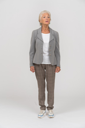 Вид спереди пожилой женщины в сером пиджаке, о чем-то спрашивающей