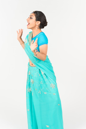 Excited young indian dancer in blue sari standing half sideways