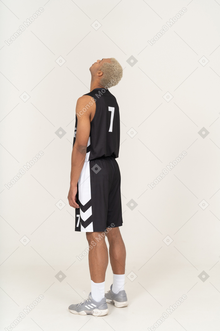 Vista posterior de tres cuartos de un joven jugador de baloncesto masculino cansado reclinado hacia atrás